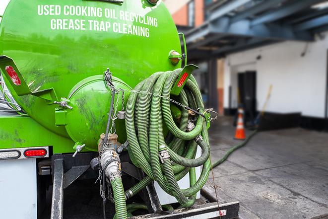 a professional plumber using a pump to empty a grease trap in Blackwood